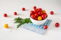 Yellow and red cherry tomatoes in a white bowl on a blue napkin. A bunch of green. Royalty Free Stock Photo