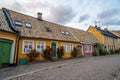 Yellow and red cottages bordered with rose bushes along a cobblestoned street in old historic part of university town Lund, Sweden