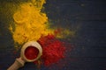 Yellow and red curry spice and paprika with a wooden spoon on a black wooden background, close-up