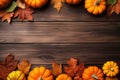 Yellow and red dried leaves and small orange pumpkins on brown wooden background, top view, copy space. Halloween, Thanksgiving