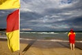 Yellow and red flags warning sign defocused female Volunteer lifesaving beach patrol standing watching tourists swimming flags Royalty Free Stock Photo