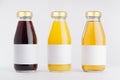 Yellow, red fruit and berries juices collection in glass bottles with cap, white blank labels in row mock up on white background. Royalty Free Stock Photo