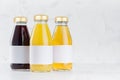 Yellow, red fruit and berries juices set in glass bottles with cap, white blank labels mock up group on white wood table in light. Royalty Free Stock Photo