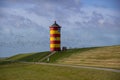 The yellow and red lighthouse of Pilsum with birds passing by