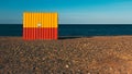 Yellow and red moving container on empty pebble beach in Europe