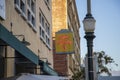 A yellow and red neon public parking sign surrounded by buildings and a tall black light post with a round light Royalty Free Stock Photo