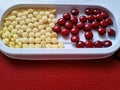 Yellow and red pills on white tray on fresh red table.