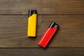 Yellow and red plastic cigarette lighters on wooden table, flat lay Royalty Free Stock Photo