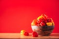 Yellow and red scotch bonnet chili peppers in wooden bowl over red background. Copy space. Royalty Free Stock Photo