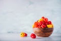 Yellow and red scotch bonnet chili peppers in wooden bowl over grey background. Copy space.