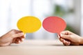 Yellow And Red Speech Bubbles Held By Hands On A Table Royalty Free Stock Photo