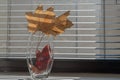 Yellow and red standing dry autumn maple leaves in transparent glass vase. Vase stands on windowsill on background of dusty window Royalty Free Stock Photo