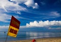 Yellow and red swim here flag against blue sky with cumulus and cirrus clouds on tropical beach in Phuket, Thailand Royalty Free Stock Photo