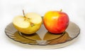 Yellow red tasty fresh cut sliced half apple on glass plate Royalty Free Stock Photo