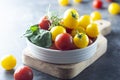 Yellow and red tomatoes in plate, isolated over dark background