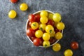 Yellow and red tomatoes in plate, isolated over dark background