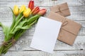 Yellow and red tulip bouquet and blank greeting card. Top view over wooden table Royalty Free Stock Photo