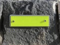 Yellow reflective rectangular road sign nailed to black stone. Yellow plastic reflector in high mountain volcanic rock. Empty