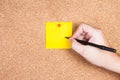 Yellow reminder sticky note on cork board with hand write to it Royalty Free Stock Photo