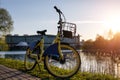Yellow rental bike in the city. Sunset near the pond