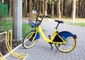 Yellow rental bike stands near the bike parking