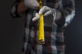 Yellow retractable tape measure tool in hands of man in shirt, closeup