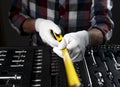 Yellow retractable tape measure tool in male hands in white construction gloves over tool case, close up