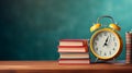 Yellow retro alarm clock, stack of books on wooden table on a blurred green school board background, back to school concept Royalty Free Stock Photo