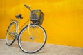 Yellow retro bicycle against a yellow wall. Vintage woman bike with a basket in front. Space for text Royalty Free Stock Photo