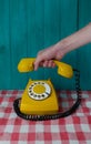 yellow retro telephone with a white disk and black numbers and a hand with a receiver on a turquoise wooden Royalty Free Stock Photo