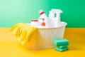 yellow reusable rubber gloves, a yellow cleaning rag and different white plastic bottles with detergents for the house