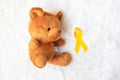 Yellow Ribbon with Bear doll on white background for supporting kid living and illness. September Childhood Cancer Awareness month Royalty Free Stock Photo