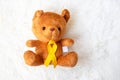 Yellow Ribbon with Bear doll on white background for supporting kid living and illness. September Childhood Cancer Awareness month Royalty Free Stock Photo