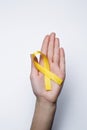 Yellow ribbon in hand, symbol Bladder cancer, Sarcoma, Bone cancer