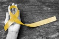 Yellow ribbon symbolic color for Sarcoma Bone cancer, Spina Bifida Awareness Month and suicide prevention on helping hand Royalty Free Stock Photo