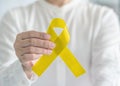 Yellow ribbon symbolic color for suicide prevention and Sarcoma Bone cancer awareness in personÃ¢â¬â¢s hand Royalty Free Stock Photo