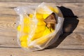 Yellow ripe bananas in plastic bag on wooden surface with sharp shadows. Fresh organic fruits on sunny day. Shopping concept. Top Royalty Free Stock Photo