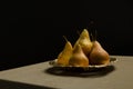 Yellow ripe pears on the vintage plate, table and tableclot on it against dark background