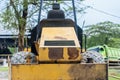 A yellow road roller that\'s on the stand by mode without the roll at a park