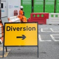 Yellow Road Sign with Arrow, Diversion: Barrier and Workers in background Royalty Free Stock Photo
