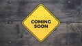 Yellow road sign saying coming soon graphic design on grey wooden digital background