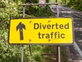 a yellow road traffic construction sign for design graphics saying diverted traffic on the side of a road and with a black upward