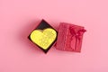 Yellow romantic gingerbread heart in a red gift box on a trendy pink background.
