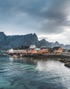 Yellow rorbu houses of Sakrisoy fishing village on a cloudy day with mountains in the background. Lofoten islands Royalty Free Stock Photo