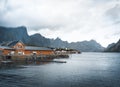 Yellow rorbu houses of Sakrisoy fishing village on a cloudy day with mountains in the background. Lofoten islands Royalty Free Stock Photo