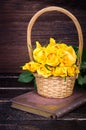 Yellow roses in a basket, vintage book on wooden background. Free space for your text Royalty Free Stock Photo