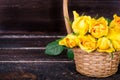 Yellow roses in a basket, vintage book on wooden background. Free space for your text Royalty Free Stock Photo