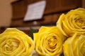 Yellow roses in foreground right and brown piano and sheet music