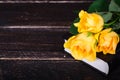Yellow roses laying on a Bible, wooden background. Free space for your text.