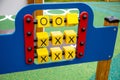 Yellow rotating cubes with tic-tac-toe on a wooden red board on a playground on a clear sunny day.